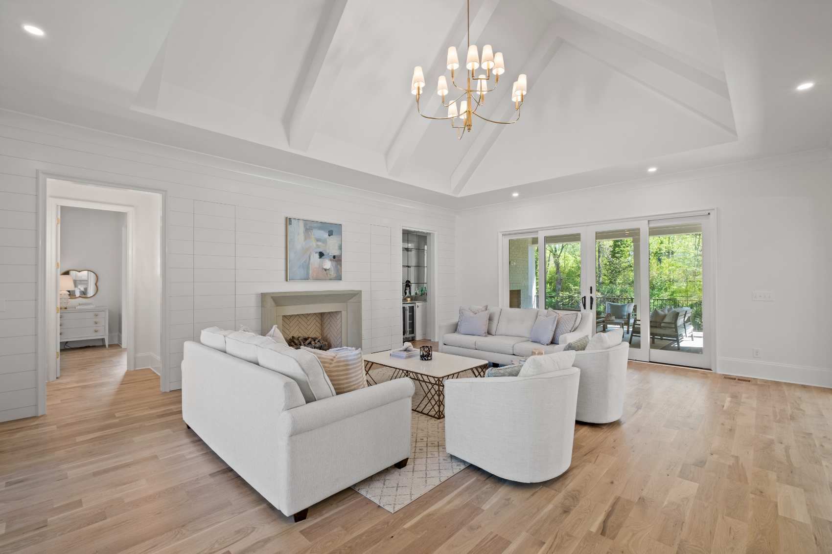 Great room with a beamed vaulted ceiling and a fireplace between glass doors